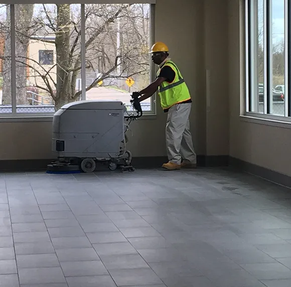 Cleaning professional operating a floor cleaning machine for commercial cleaning services.