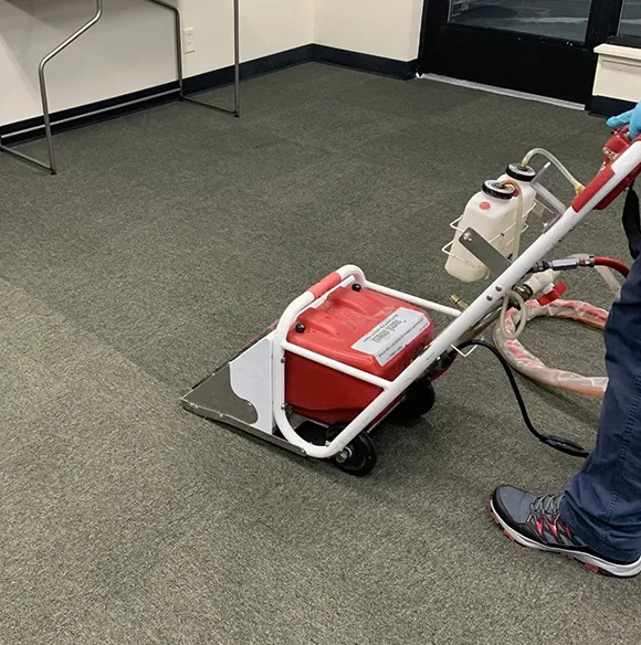Professional operating a floor cleaning machine on a carpeted floor in Ann Arbor MI.
