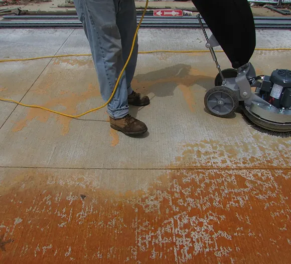 Shoes standing on concrete floor with debris, representing concrete floor cleaning service in Ann Arbor MI.