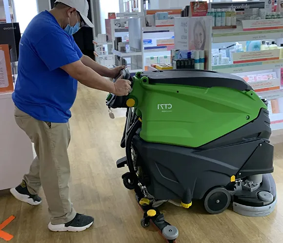 Professional operating a floor scrubber for stripping and waxing services in Grand Rapids MI.