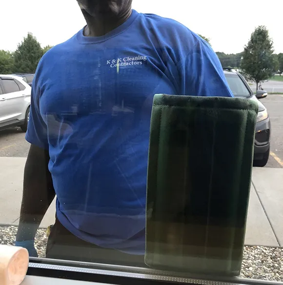 Professional cleaner wiping a window at a commercial building in Kalamazoo MI.