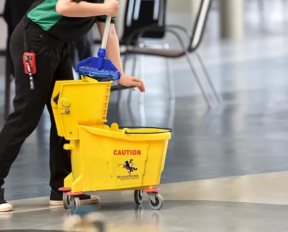 Janitorial staff mopping a floor with mop bucket and wet floor sign in Detroit MI.