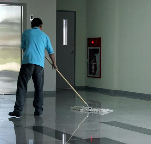 Janitorial staff mopping a hallway floor during nightly cleaning services in Lansing MI.