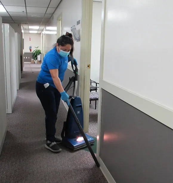 Janitorial cleaner vacuuming a carpeted hallway in an office building in Ann Arbor MI.