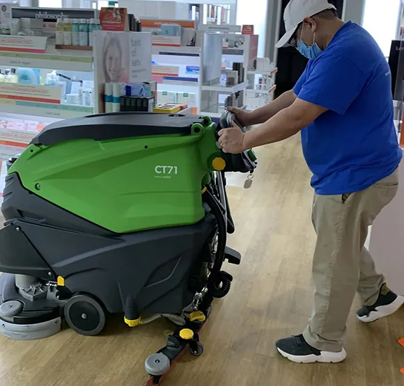 Professional cleaner operating a walk-behind floor scrubber machine in Detroit MI.