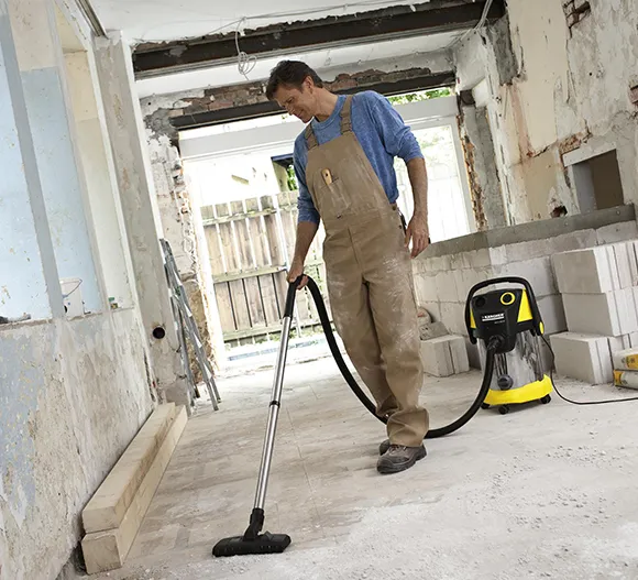 Cleaning professional using a large vacuum cleaner in a room under construction or renovation in Lansing MI.