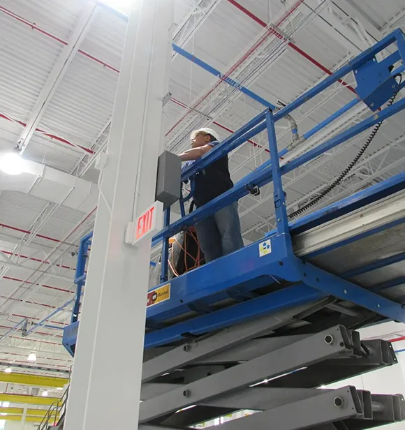 Cleaning professional on a scissor lift cleaning high areas during final construction cleanup in Grand Rapids MI.