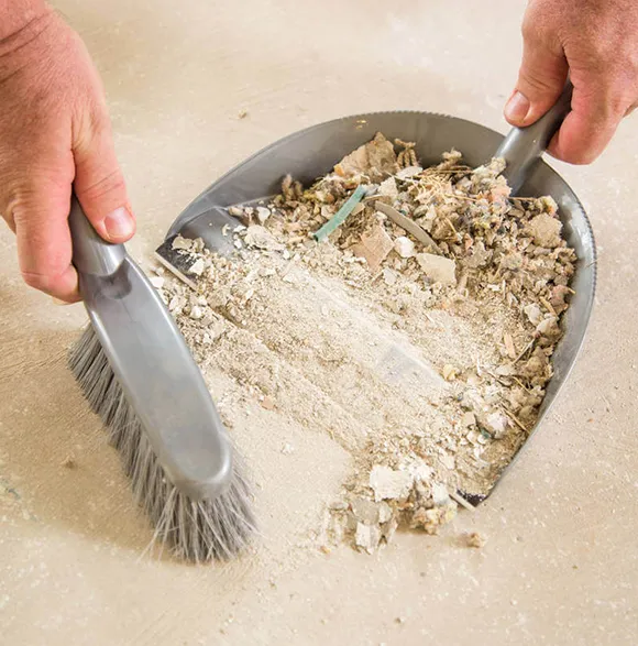 Brush and dustpan collecting construction debris during cleanup in Ann Arbor MI.