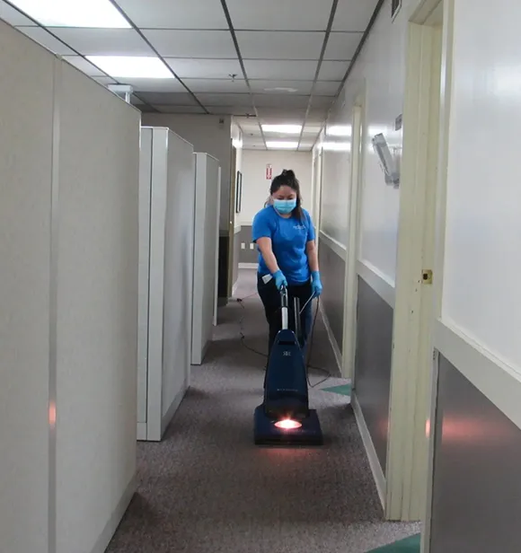 Janitorial professional using a floor cleaning machine in an office hallway in Kalamazoo MI.