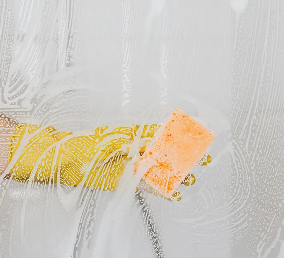 Professional cleaner wiping a white surface with a microfiber cloth and spray bottle in Grand Rapids MI.