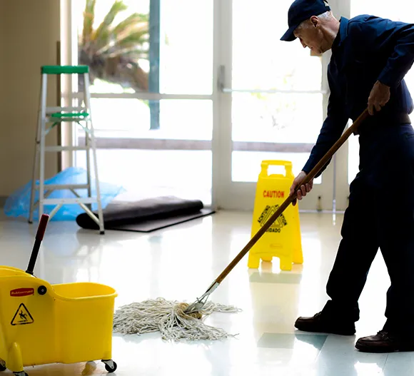 Janitorial cleaner mopping a commercial floor with a wet floor sign in Detroit MI.