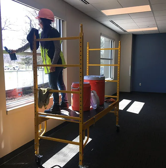Professional cleaner on scaffolding cleaning windows inside a commercial building in Lansing MI
