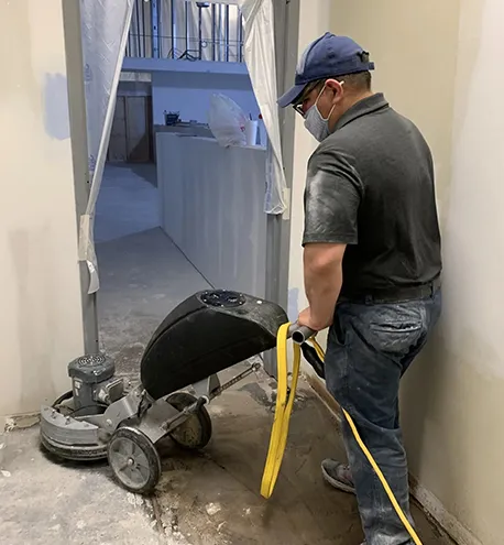 Cleaning professional using floor buffer on a hard surface.